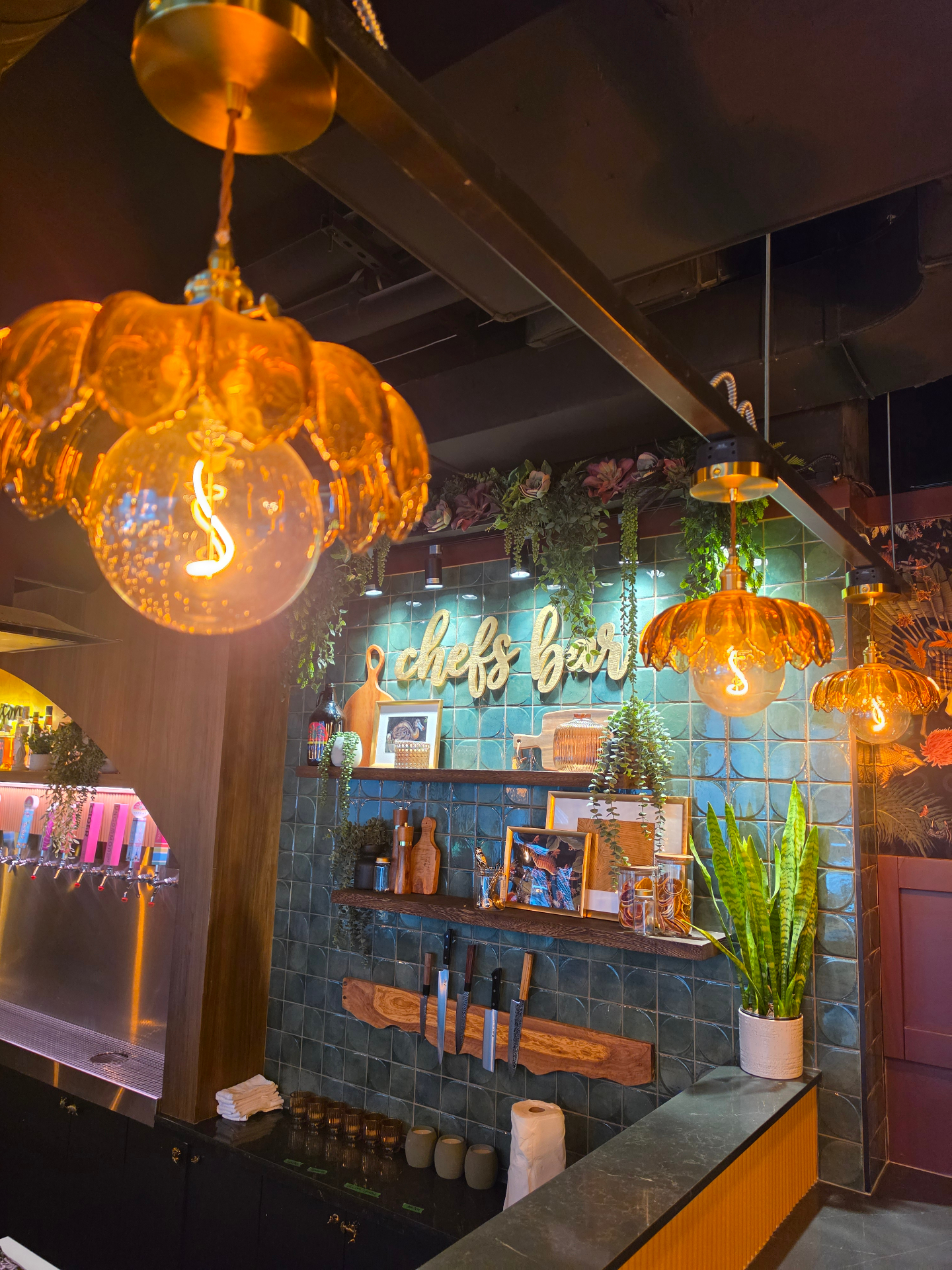 The Vaycay taproom chef's bar with amber pendant lights and tropical tile
